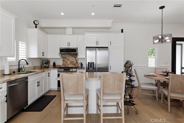 kitchen featuring visible vents, a sink, light wood-type flooring, white cabinetry, and stainless steel appliances