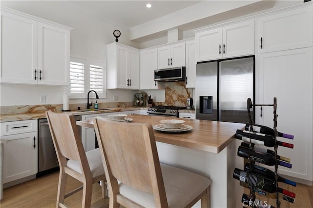 kitchen featuring a sink, white cabinetry, wood counters, stainless steel appliances, and light wood-style flooring