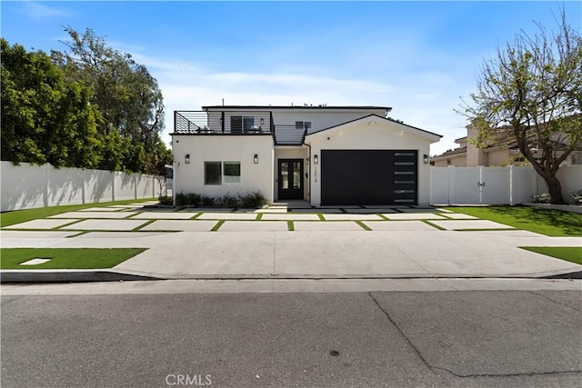 view of front of property with a balcony, stucco siding, driveway, an attached garage, and fence