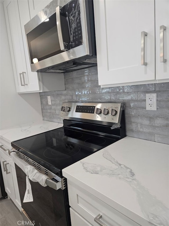 kitchen with appliances with stainless steel finishes, backsplash, and white cabinets