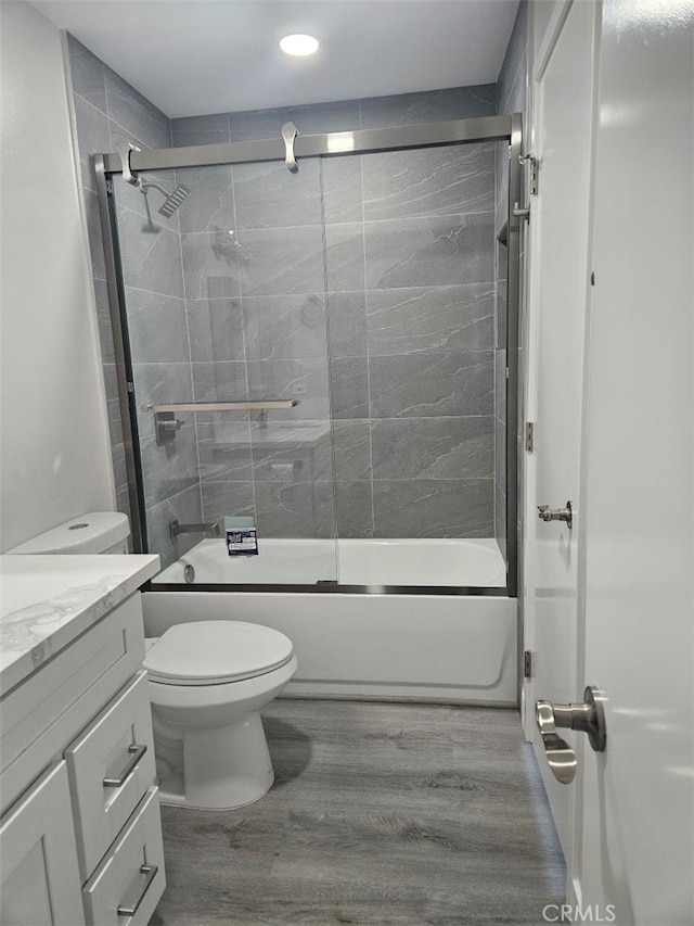 bathroom featuring enclosed tub / shower combo, vanity, toilet, and wood finished floors