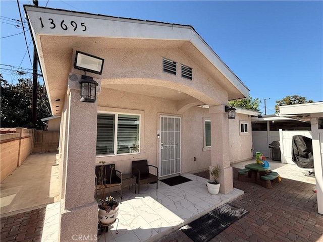 rear view of property featuring a patio area, fence, and stucco siding