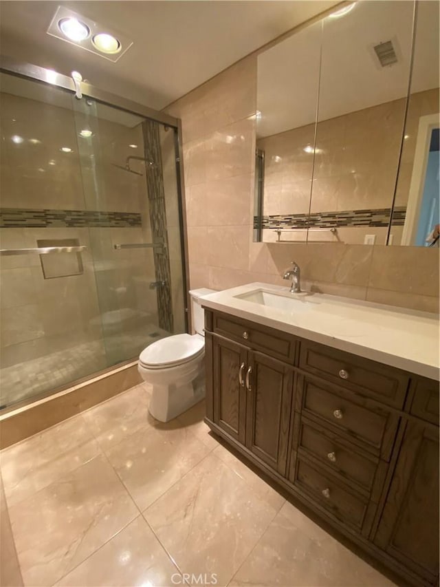 full bathroom featuring tile walls, visible vents, toilet, a shower stall, and vanity