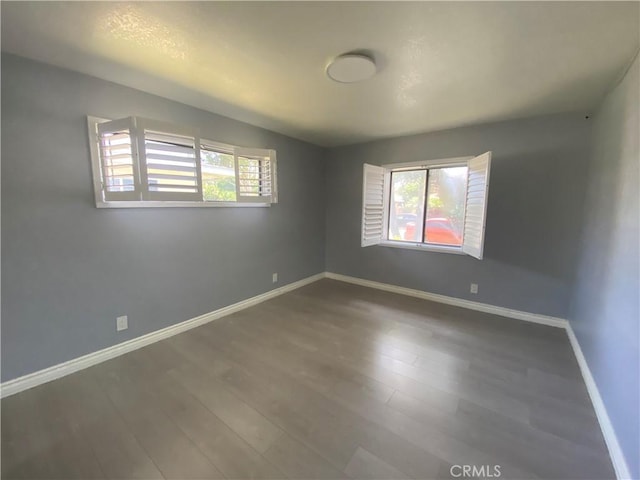 spare room featuring a healthy amount of sunlight, vaulted ceiling, and wood finished floors