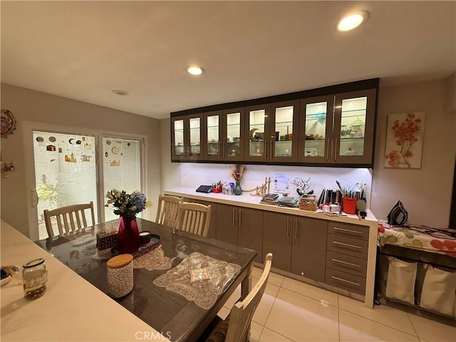 interior space featuring light tile patterned floors, glass insert cabinets, light countertops, and recessed lighting