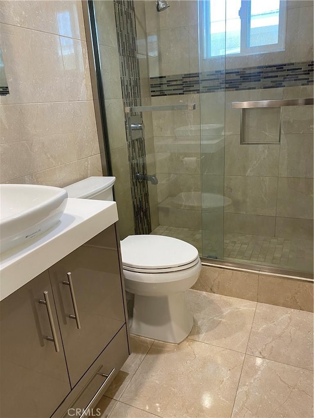 bathroom with toilet, a shower stall, tile walls, and vanity