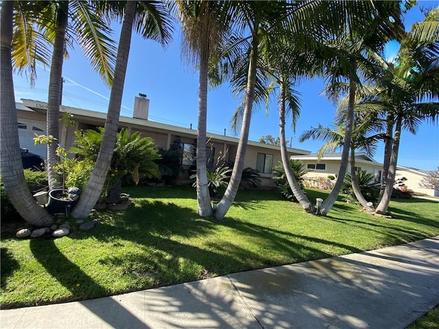 view of front of house with an attached garage, a chimney, and a front yard