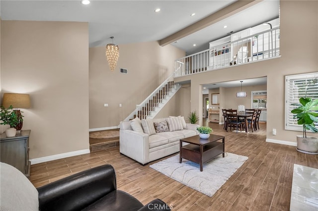 living area with baseboards, visible vents, beamed ceiling, stairs, and wood finish floors