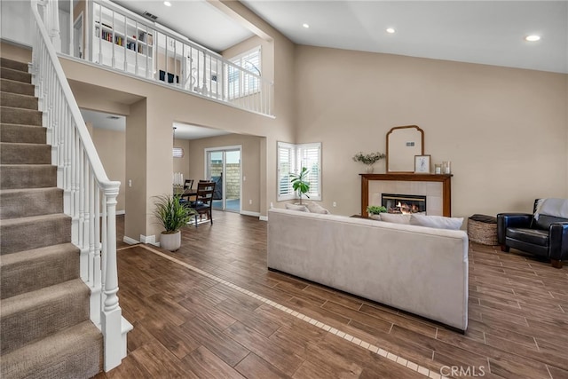 living room with wood tiled floor, plenty of natural light, stairway, and a tile fireplace