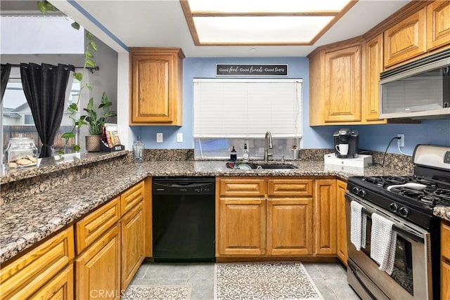 kitchen with brown cabinets, stone countertops, stainless steel appliances, and a sink