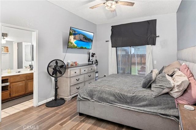 bedroom with wood finished floors, baseboards, ensuite bath, ceiling fan, and a textured ceiling