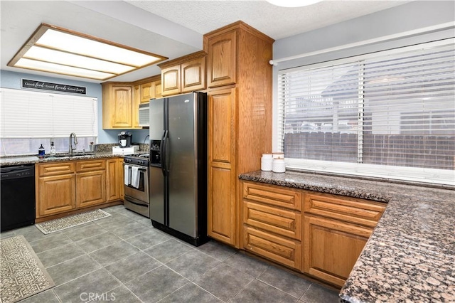 kitchen featuring fridge with ice dispenser, a sink, dark stone counters, gas range, and dishwasher