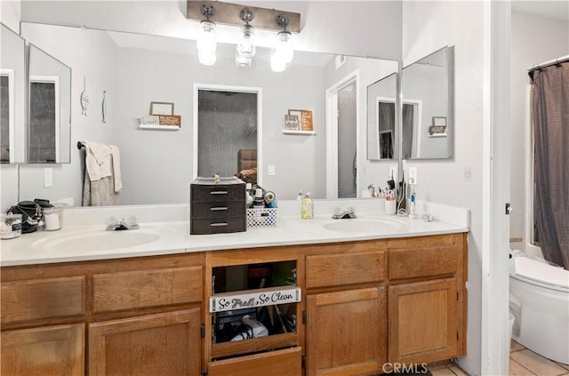 bathroom with double vanity, toilet, and a sink