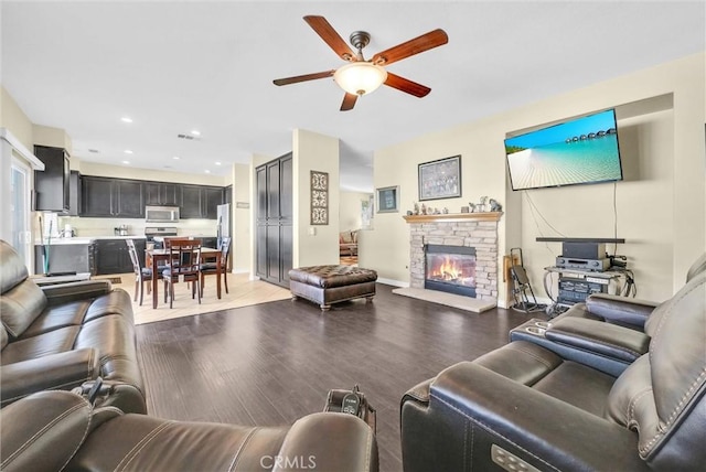 living room featuring ceiling fan, recessed lighting, a fireplace, baseboards, and light wood-style floors