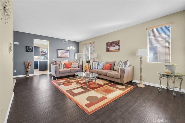 living room featuring a notable chandelier, wood finished floors, visible vents, and baseboards