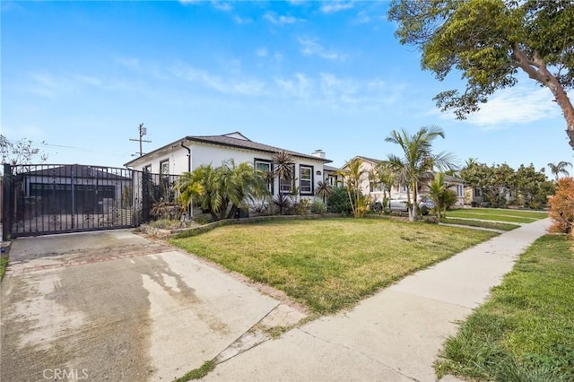 view of front of house with stucco siding, concrete driveway, a front lawn, and a gate