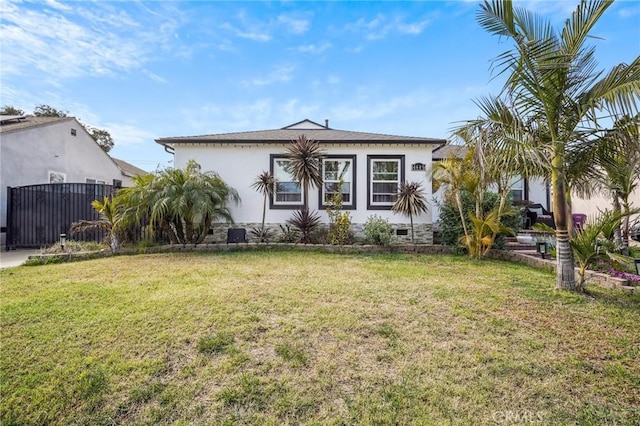 bungalow-style home with stucco siding, a front yard, and fence