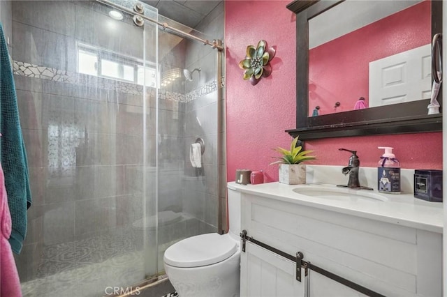 full bathroom with toilet, a stall shower, vanity, and a textured wall