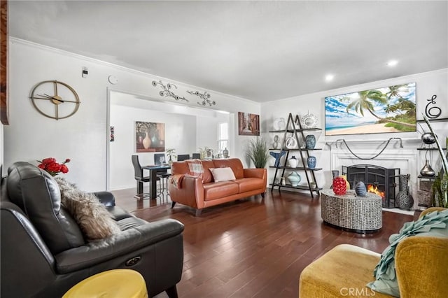 living area with wood-type flooring, a lit fireplace, and ornamental molding