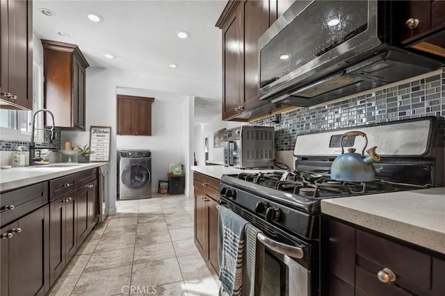 kitchen with tasteful backsplash, dark brown cabinets, appliances with stainless steel finishes, washer / clothes dryer, and a sink