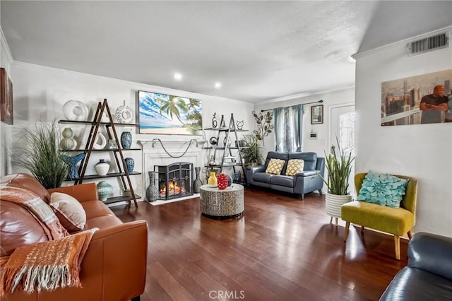 sitting room with visible vents, crown molding, a lit fireplace, and wood finished floors