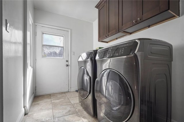 washroom with light tile patterned floors, cabinet space, and washer and clothes dryer