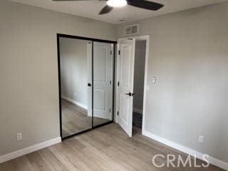 unfurnished bedroom featuring visible vents, baseboards, ceiling fan, light wood-type flooring, and a closet