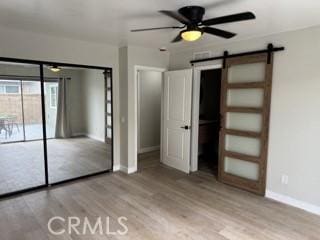 unfurnished bedroom featuring access to exterior, wood finished floors, baseboards, and a barn door