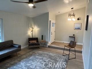 sitting room featuring lofted ceiling, wood finished floors, a ceiling fan, and baseboards