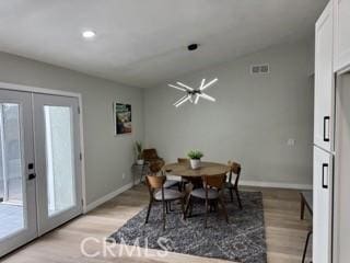 dining space with baseboards, french doors, vaulted ceiling, and light wood-style floors