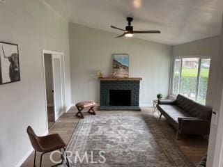 living room with vaulted ceiling, a brick fireplace, a ceiling fan, and baseboards