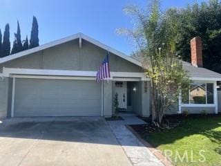 ranch-style home with a garage, driveway, a front lawn, and stucco siding