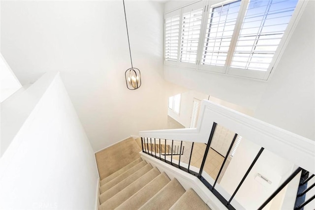 staircase with a notable chandelier, plenty of natural light, and a towering ceiling