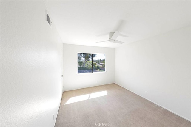 spare room featuring a ceiling fan, visible vents, and carpet flooring