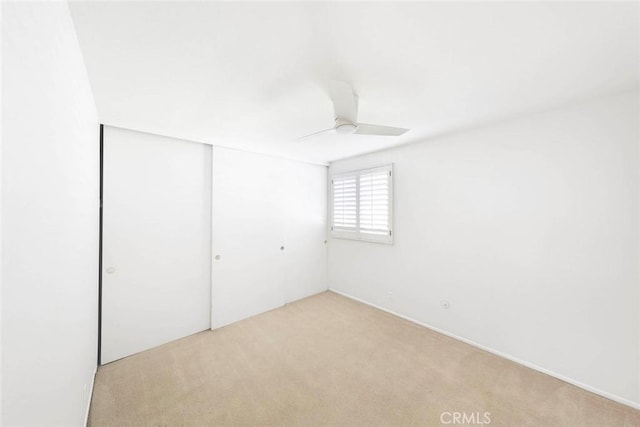 unfurnished bedroom with a ceiling fan, a closet, and light colored carpet