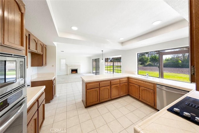 kitchen featuring stainless steel appliances, a raised ceiling, a lit fireplace, and light tile patterned floors