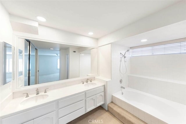 bathroom featuring tiled shower / bath combo, double vanity, a sink, and recessed lighting