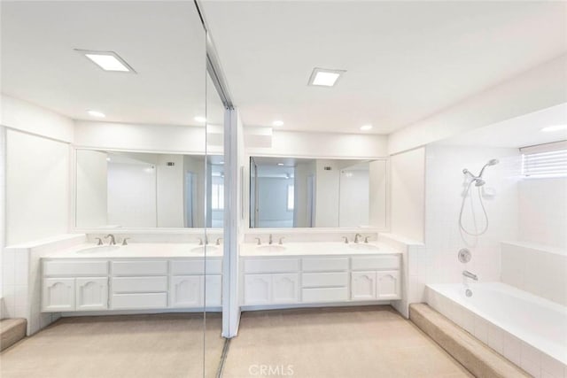 full bath featuring double vanity, tiled shower / bath, and a sink