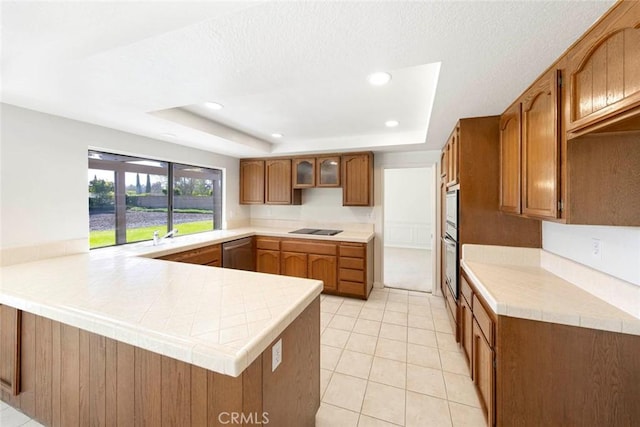 kitchen with black electric stovetop, a peninsula, dishwasher, a tray ceiling, and brown cabinetry