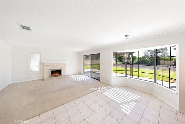 unfurnished living room with light colored carpet, a healthy amount of sunlight, visible vents, and a tile fireplace