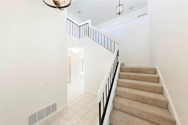 stairway featuring tile patterned flooring, visible vents, a towering ceiling, and baseboards