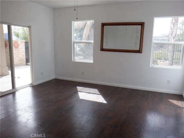 spare room with dark wood-type flooring and baseboards