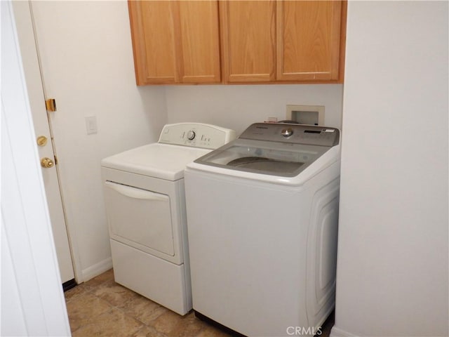 washroom featuring washing machine and dryer, cabinet space, and baseboards