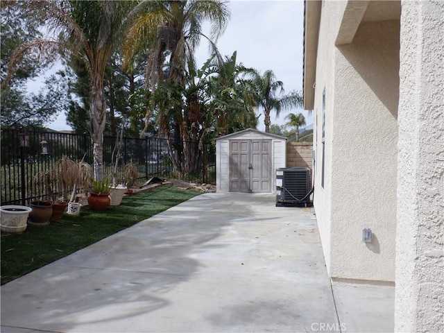 view of patio / terrace featuring a storage unit, central AC unit, an outbuilding, and a fenced backyard