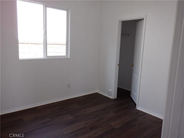 empty room featuring baseboards and dark wood-style flooring