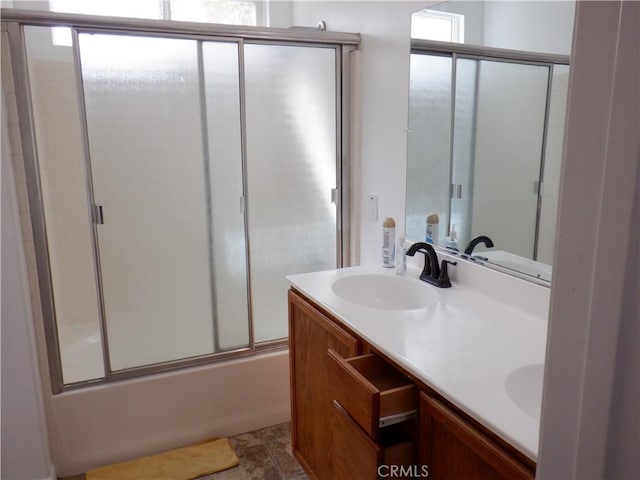 full bath featuring double vanity, bath / shower combo with glass door, and a sink