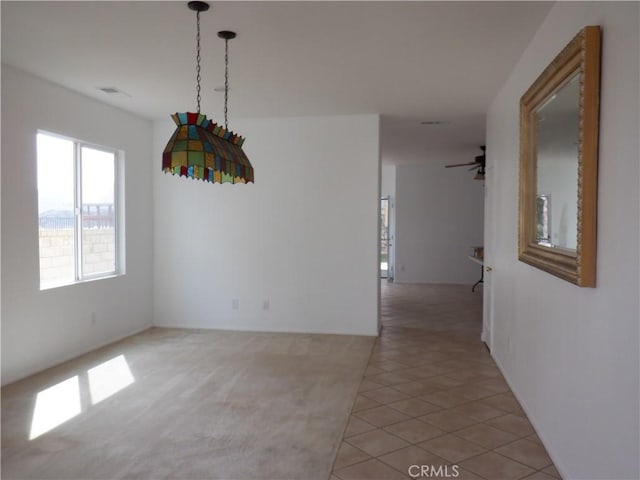 unfurnished dining area with ceiling fan, visible vents, light tile patterned floors, and light carpet