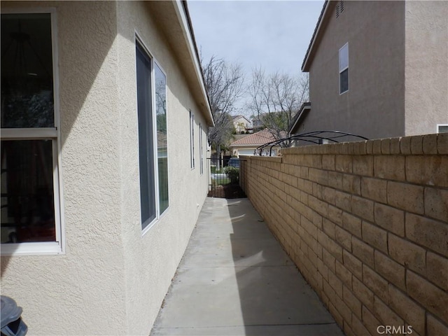view of side of home featuring stucco siding and fence