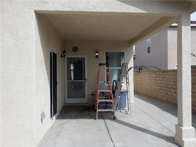 doorway to property with a patio area, stucco siding, and fence