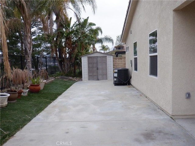 view of patio / terrace featuring a fenced backyard, a shed, cooling unit, and an outdoor structure